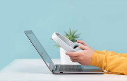 Un apprenant assis devant son ordinateur portable, avec un casque entre les mains.